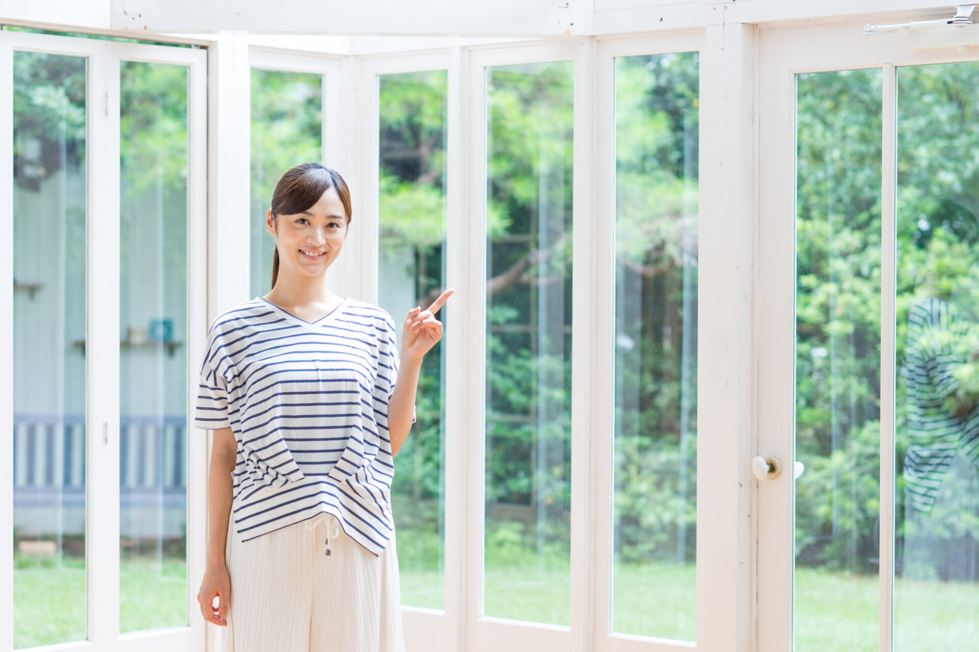 サンルームで指さす女性