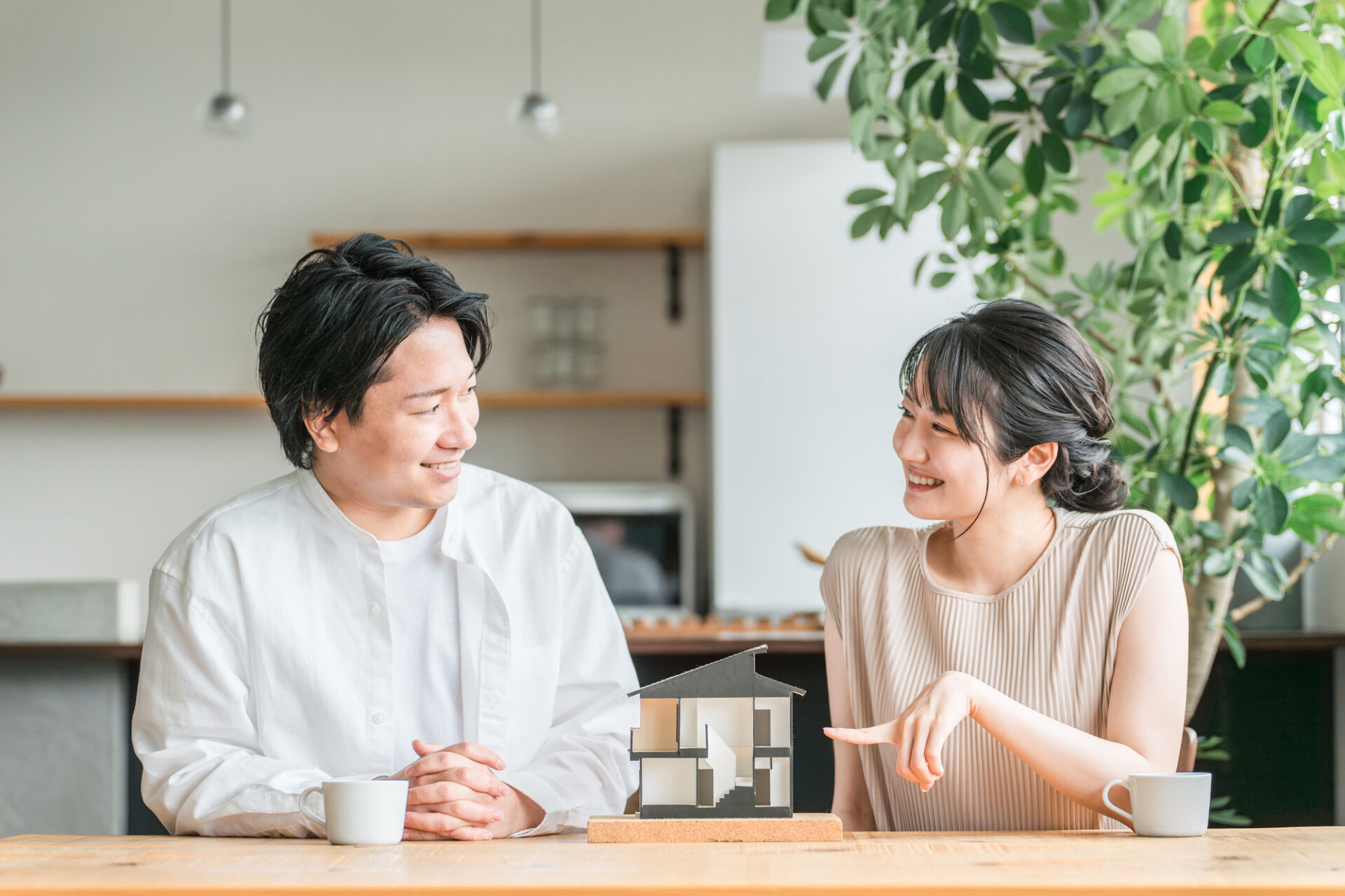 住宅模型を見て家づくりの予算を話し合う夫婦