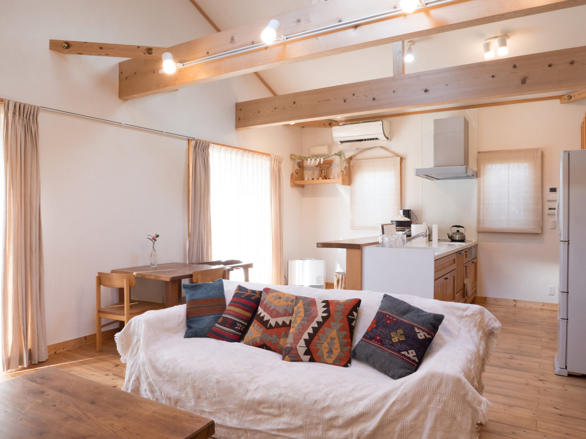 木の梁と温かみのある内装が特徴のLDK。昭和風デザインと現代トレンドの違いを比較するための古く見える住宅イメージ。