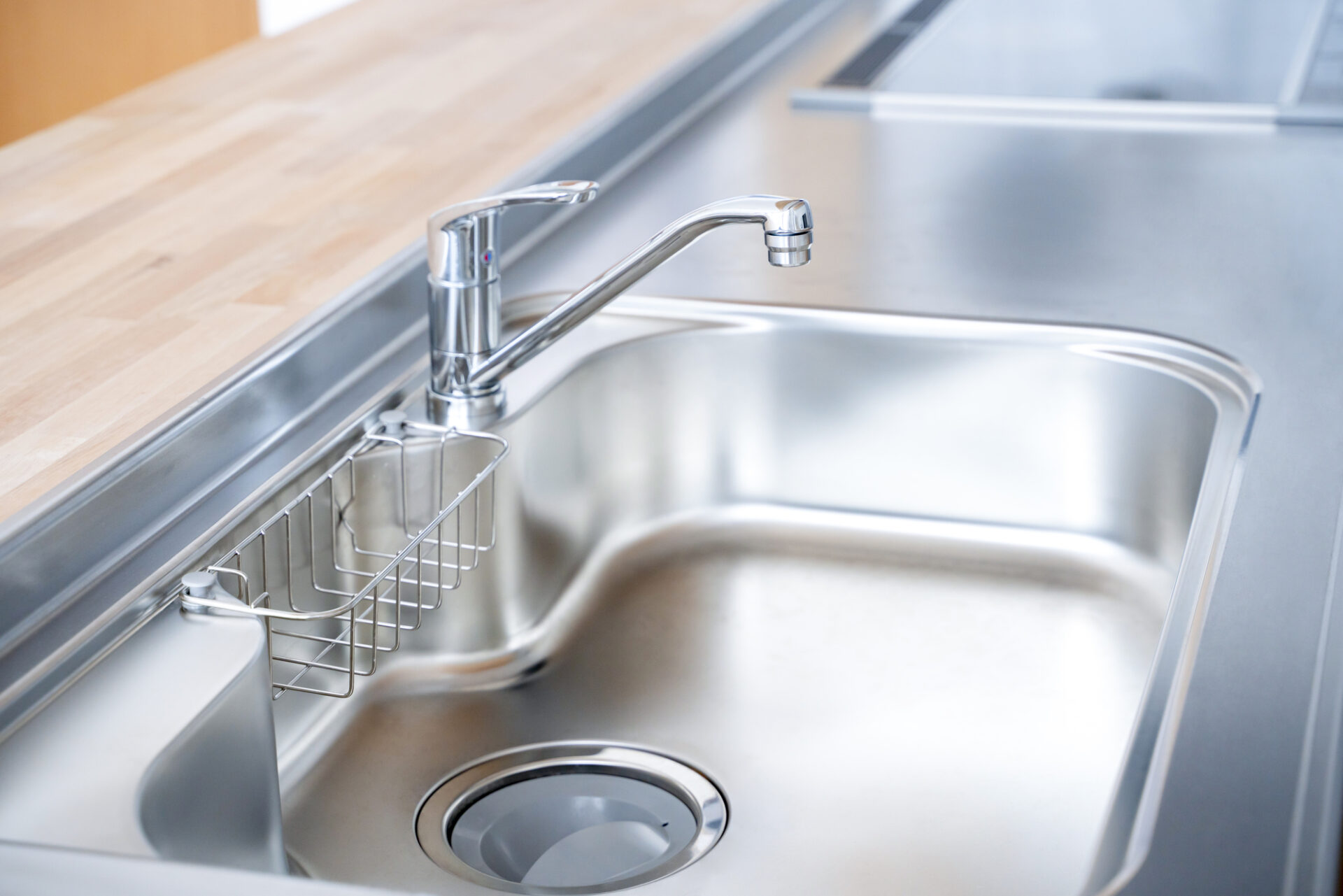 銀色のキッチン水栓のクローズアップ。2025年の住宅トレンドでは、マットブラックなどの水栓が人気で、古く見えない設備選びのポイント。